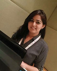 Young woman with dark hair wearing a black and white patterned top, smiling indoors