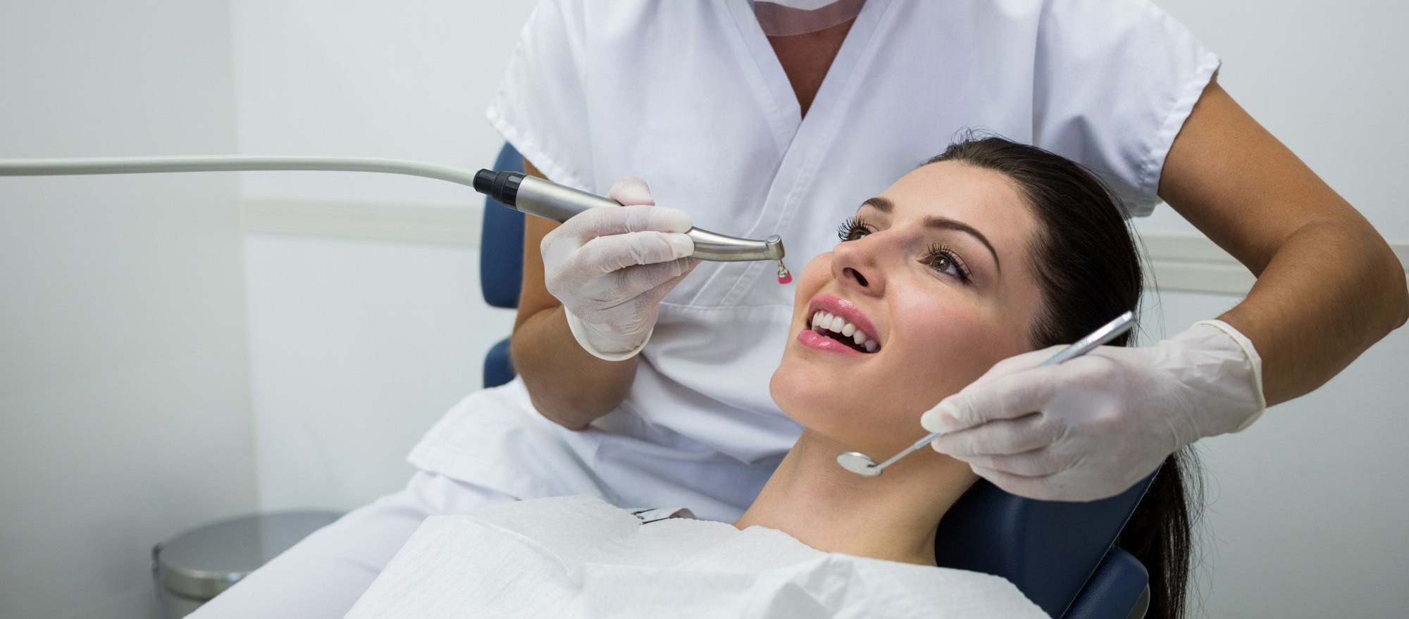 Dentist performing dental procedure on a smiling female patient